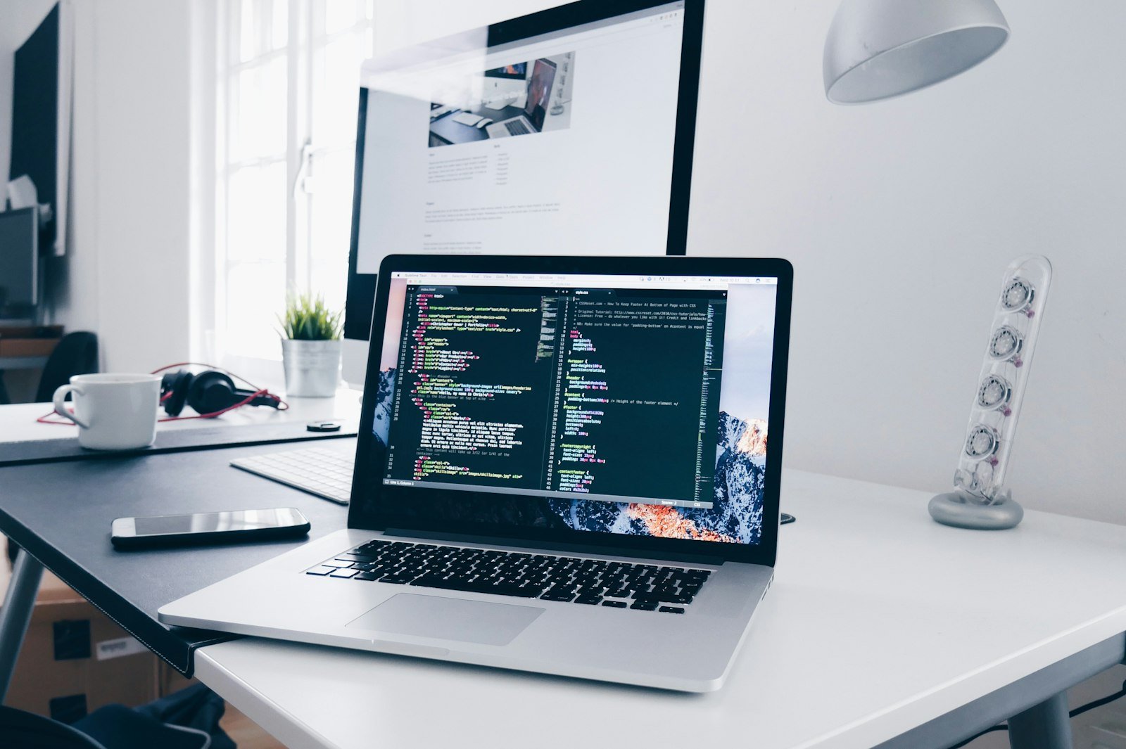 Laptop showing website code on a tidy desk