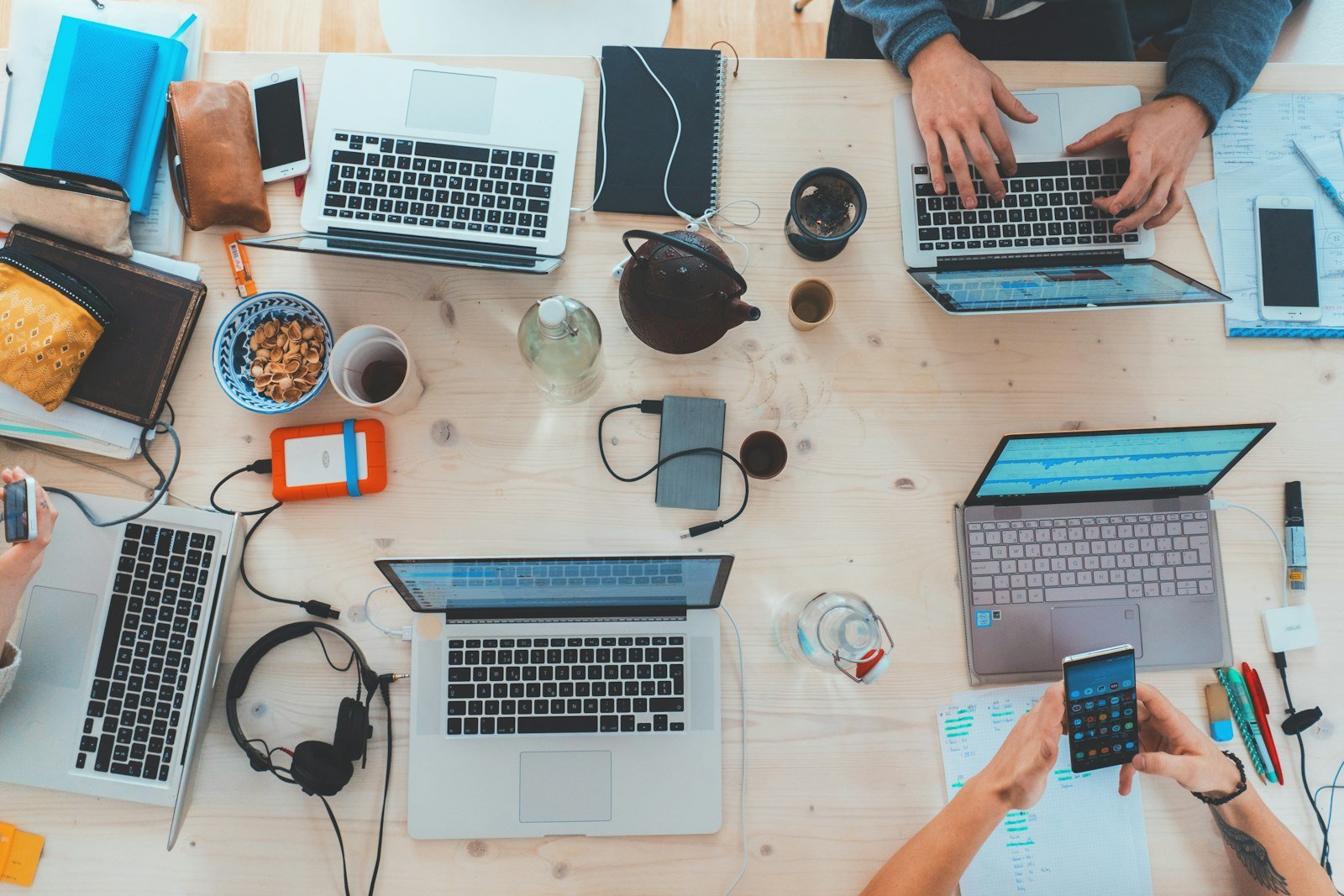 Overhead view of laptops and notebooks on a shared work table
