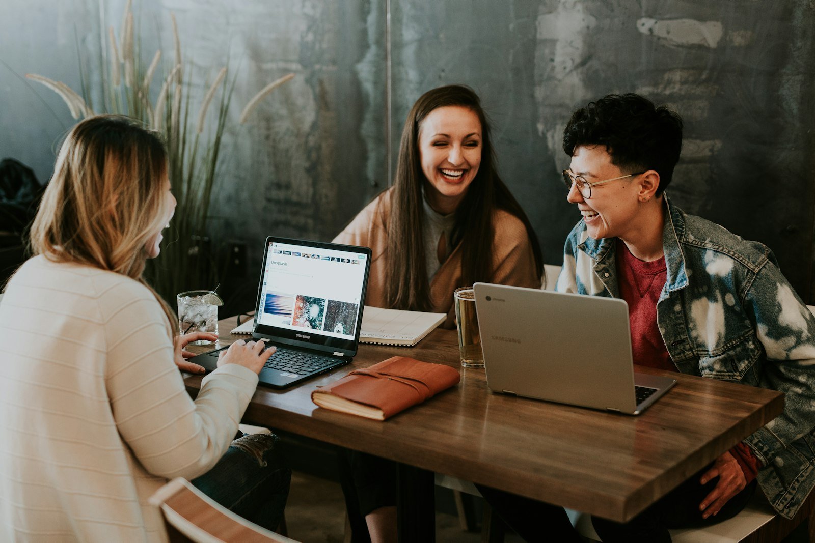 Team members laughing together around a table with laptops